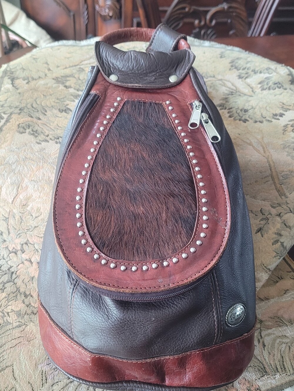 America West soft brown leather sling backpack, with studs & hair on front flap.